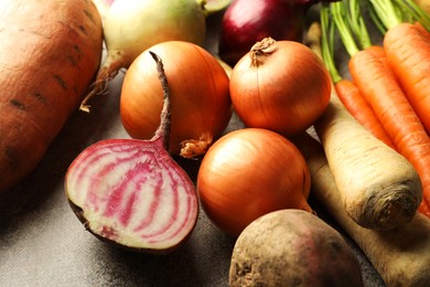 Photo of Different root vegetables on grey table, closeup