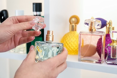 Photo of Woman taking bottle of perfume from shelf in store, closeup