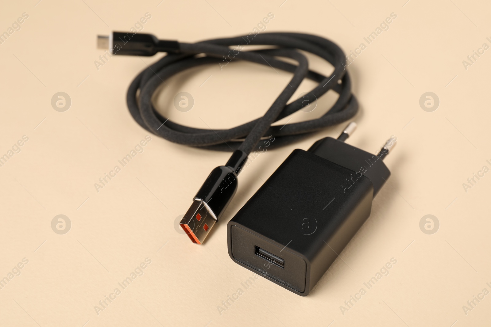USB power adapter and charge cable on beige background, closeup Photo of USB power adapter and charge cable on beige background, closeup