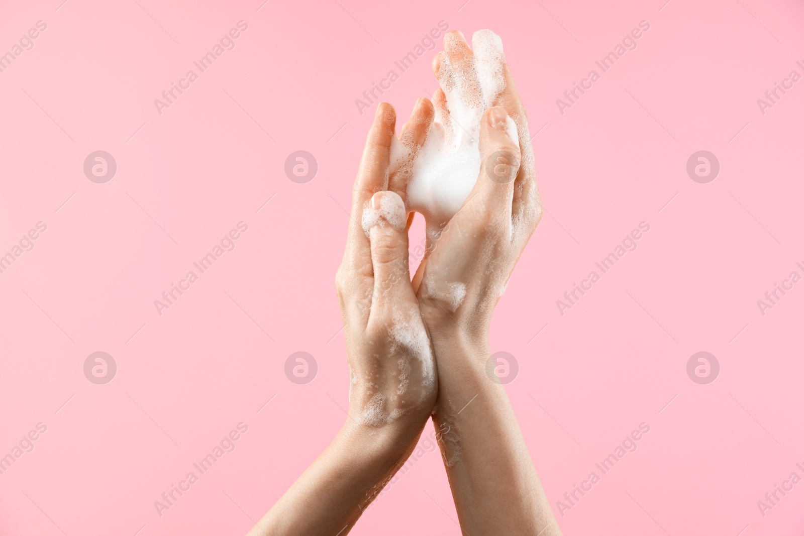 Photo of Woman washing hands with foaming soap on pink background, closeup. Hygiene