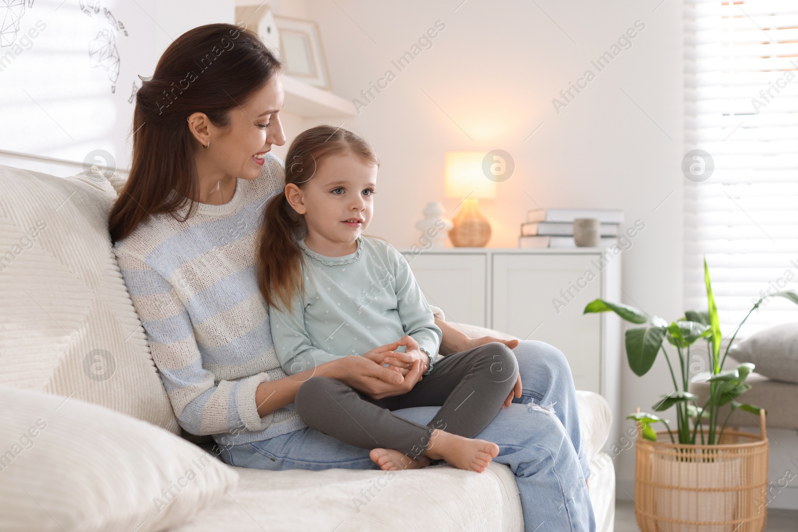 Photo of Happy mother with her cute little daughter on sofa at home