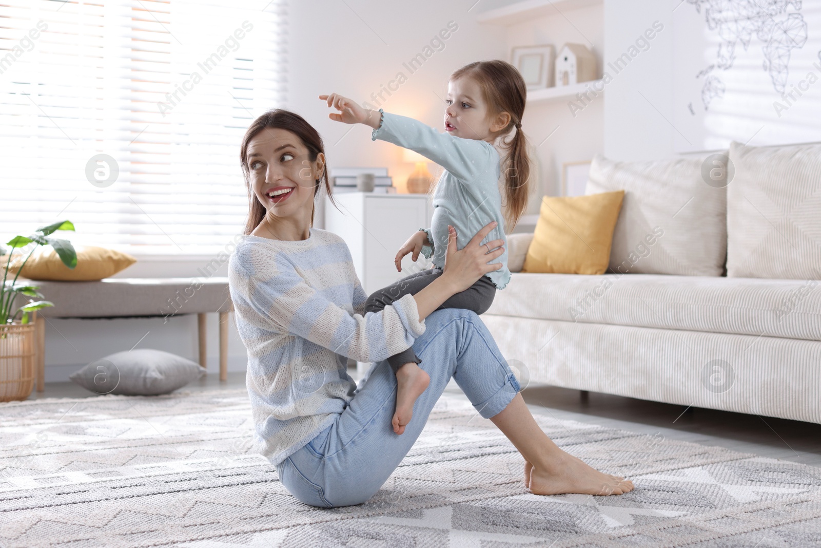 Photo of Happy mother with her cute little daughter on carpet at home