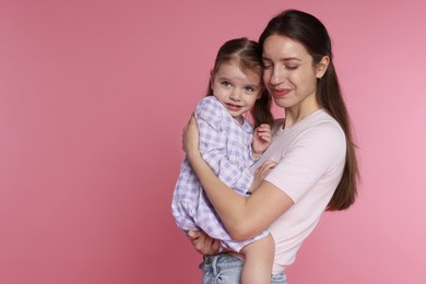 Photo of Beautiful mother with her cute little daughter on pink background, space for text