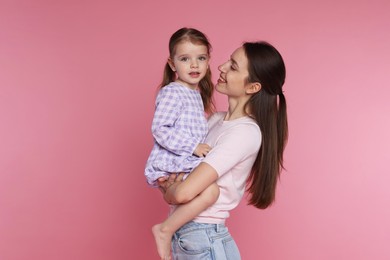 Happy mother with her cute little daughter on pink background