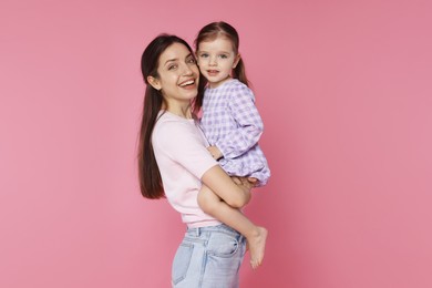 Photo of Portrait of happy mother with her cute little daughter on pink background