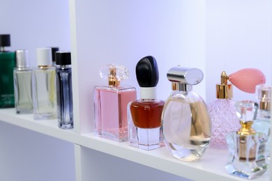 Photo of Different bottles of luxury perfume on shelf in store, closeup