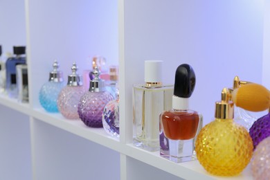 Photo of Different bottles of luxury perfume on shelf in store, closeup