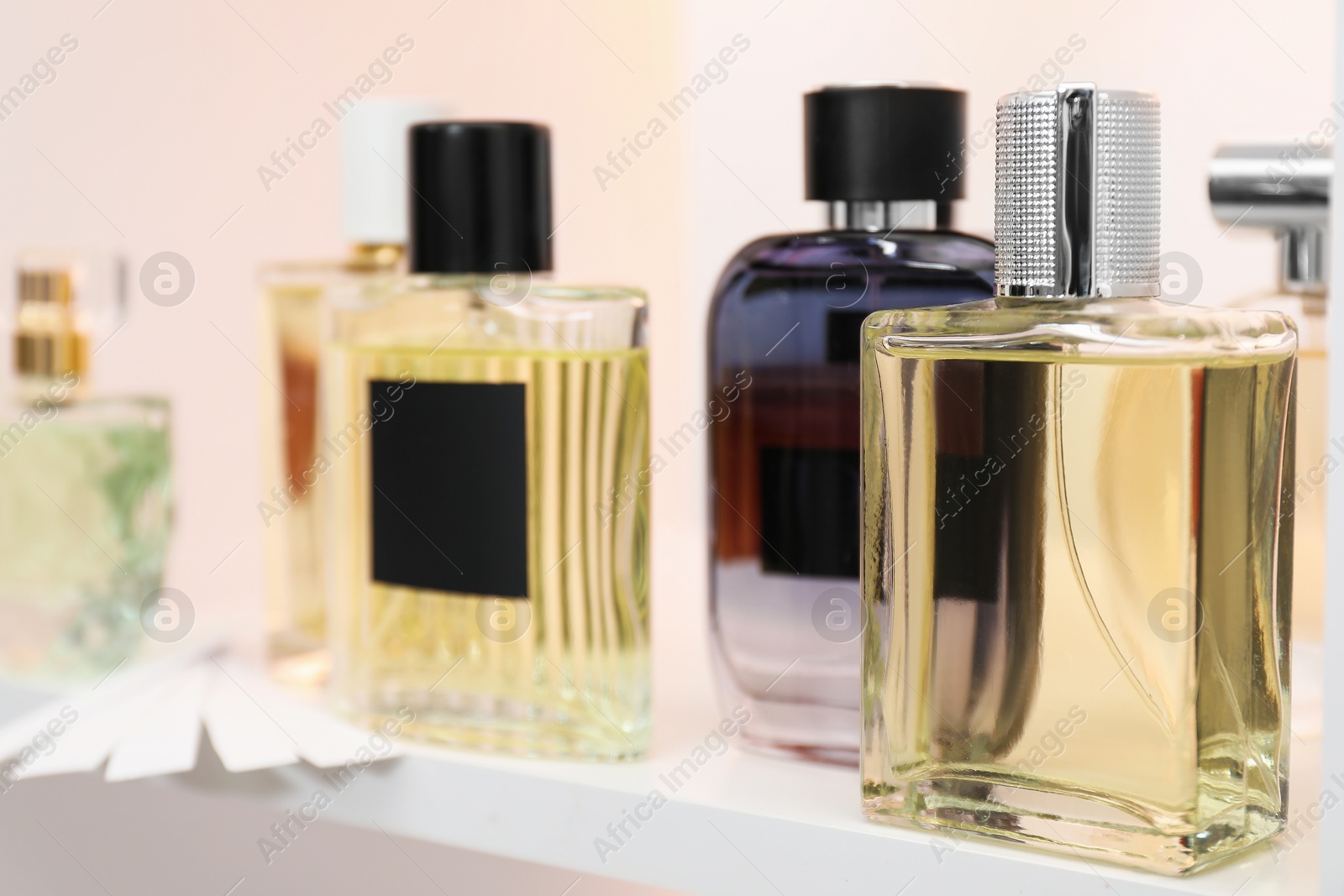 Photo of Different bottles of luxury perfume and fragrance blotters on shelf in store, closeup