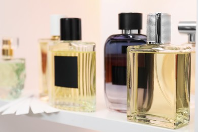 Different bottles of luxury perfume and fragrance blotters on shelf in store, closeup