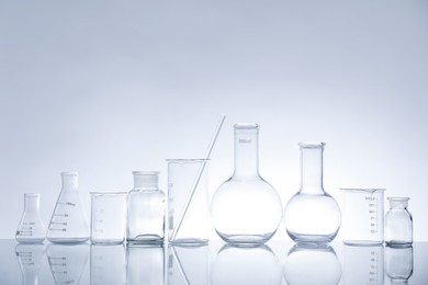 Photo of Laboratory glassware on mirror surface against light background