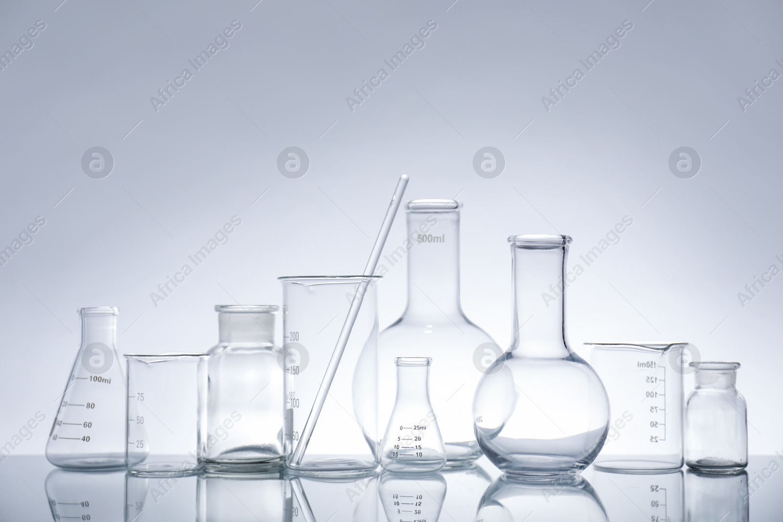 Photo of Laboratory glassware on mirror surface against light background