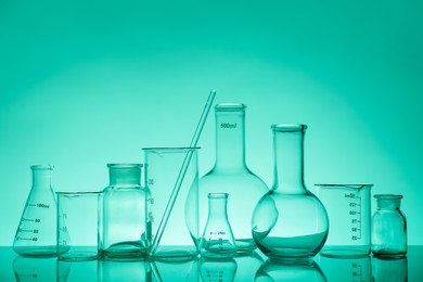 Laboratory glassware on mirror surface against green background