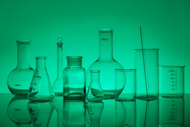 Laboratory glassware on mirror surface against green background