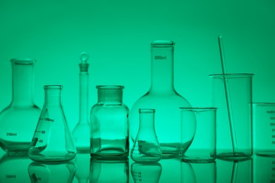 Photo of Laboratory glassware on mirror surface against green background