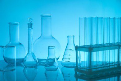 Laboratory glassware on mirror surface against light blue background