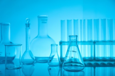 Laboratory glassware on mirror surface against light blue background