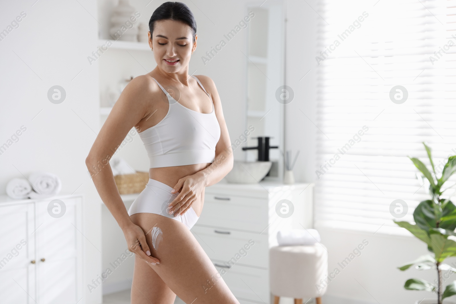 Photo of Woman applying anti cellulite cream indoors. Space for text