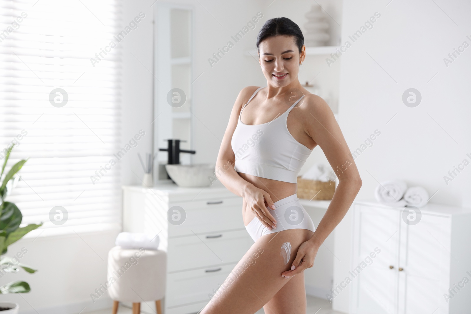 Photo of Woman applying anti cellulite cream indoors. Space for text