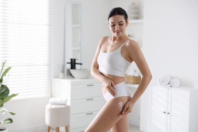 Woman applying anti cellulite cream indoors. Space for text