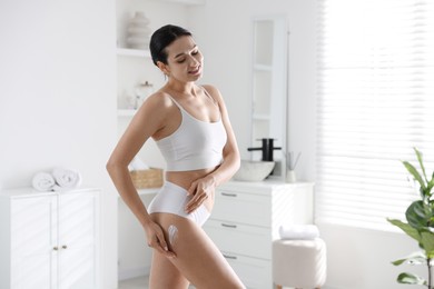 Photo of Woman applying anti cellulite cream indoors. Space for text