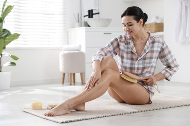 Photo of Woman doing anti cellulite massage with brush indoors. Space for text