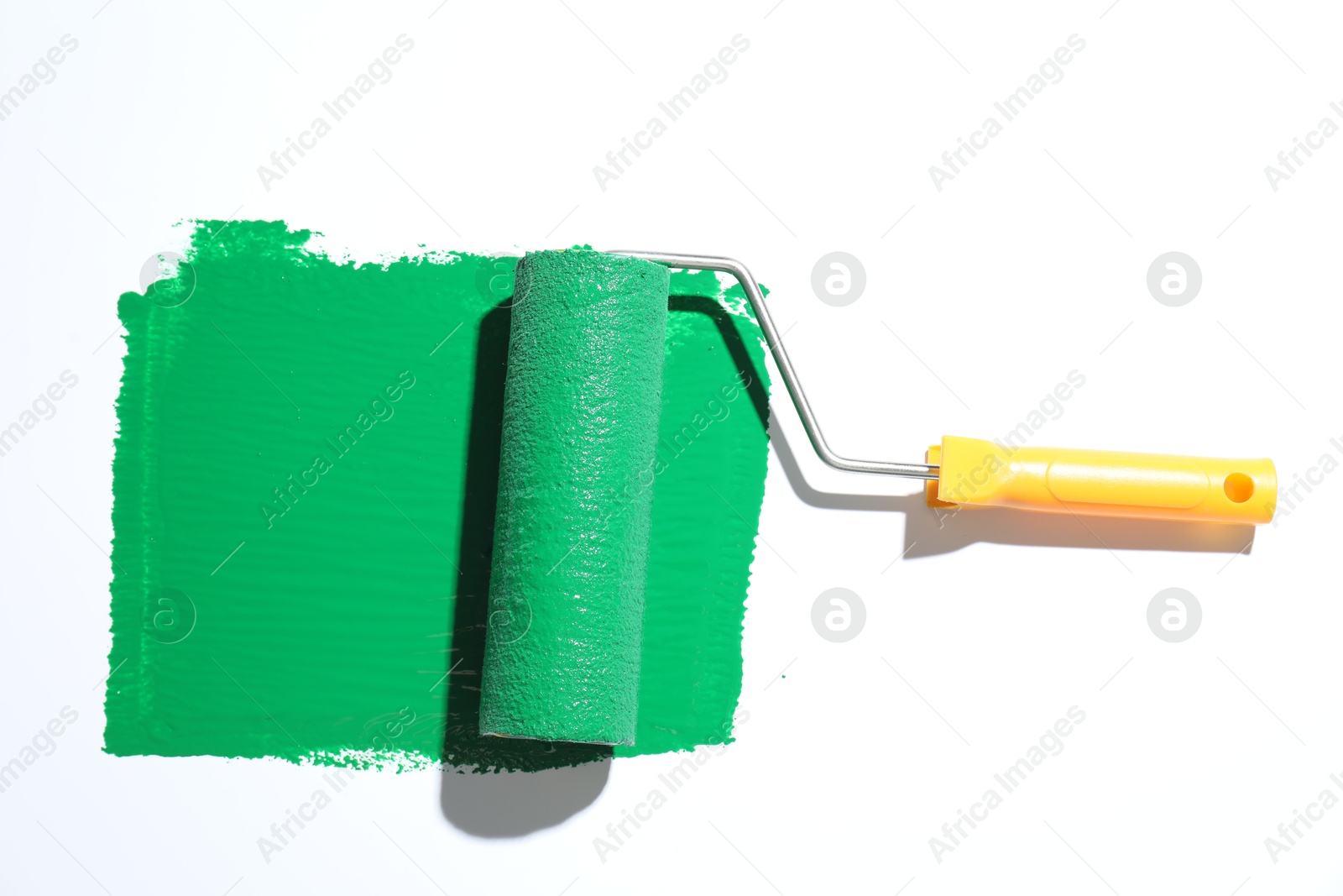 Photo of Smear of green paint and roller on white background, top view