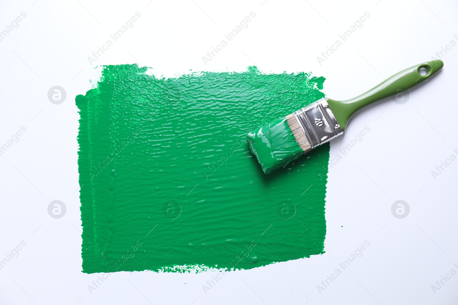 Photo of Smear of green paint and brush on white background, top view