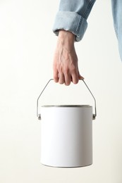 Photo of Woman holding bucket of paint on white background, closeup