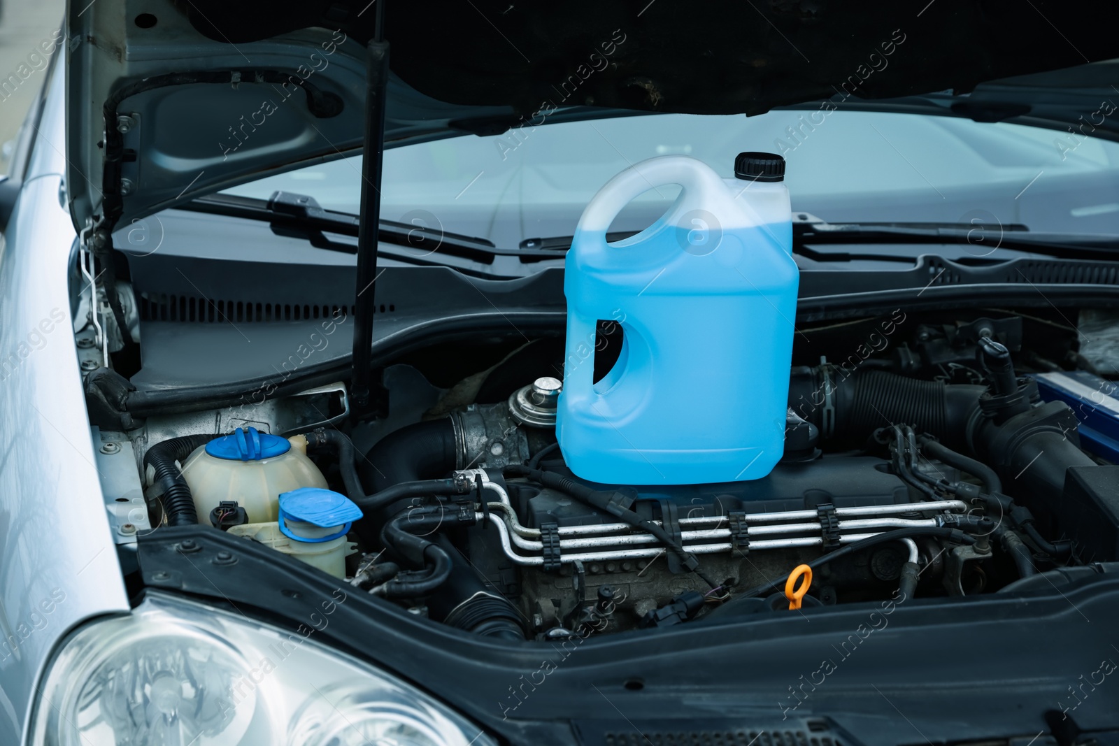 Antifreeze in plastic canister under hood of car Photo of Antifreeze in plastic canister under hood of car