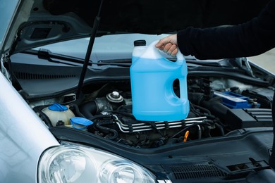 Photo of Man with canister of antifreeze near car, closeup