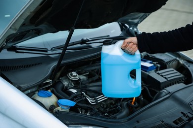 Photo of Man with canister of antifreeze near car, closeup