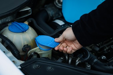 Photo of Man opening car windshield washer reservoir, closeup