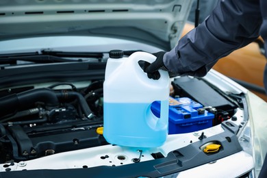 Photo of Man with canister of antifreeze near car, closeup