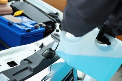 Photo of Man filling car radiator with antifreeze, closeup view