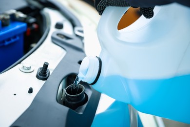 Photo of Man filling car radiator with antifreeze, closeup view