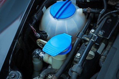 Photo of Windshield washer and coolant reservoirs in engine compartment, closeup