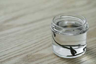 Photo of Medicinal leeches in glass jar on wooden table, closeup. Space for text