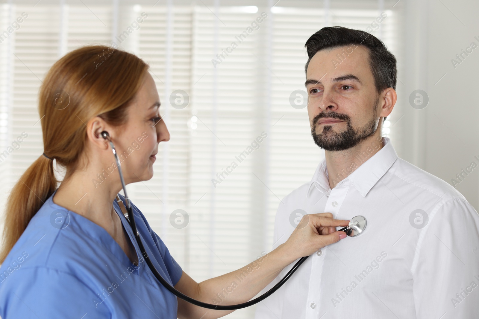 Photo of Cardiologist with stethoscope listening patient's heartbeat in hospital