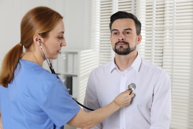 Photo of Cardiologist with stethoscope listening patient's heartbeat in hospital