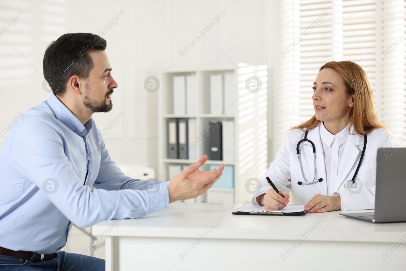 Photo of Man having consultation with cardiologist at desk in clinic