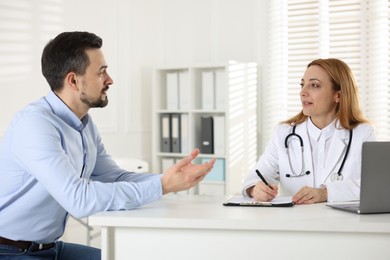 Man having consultation with cardiologist at desk in clinic