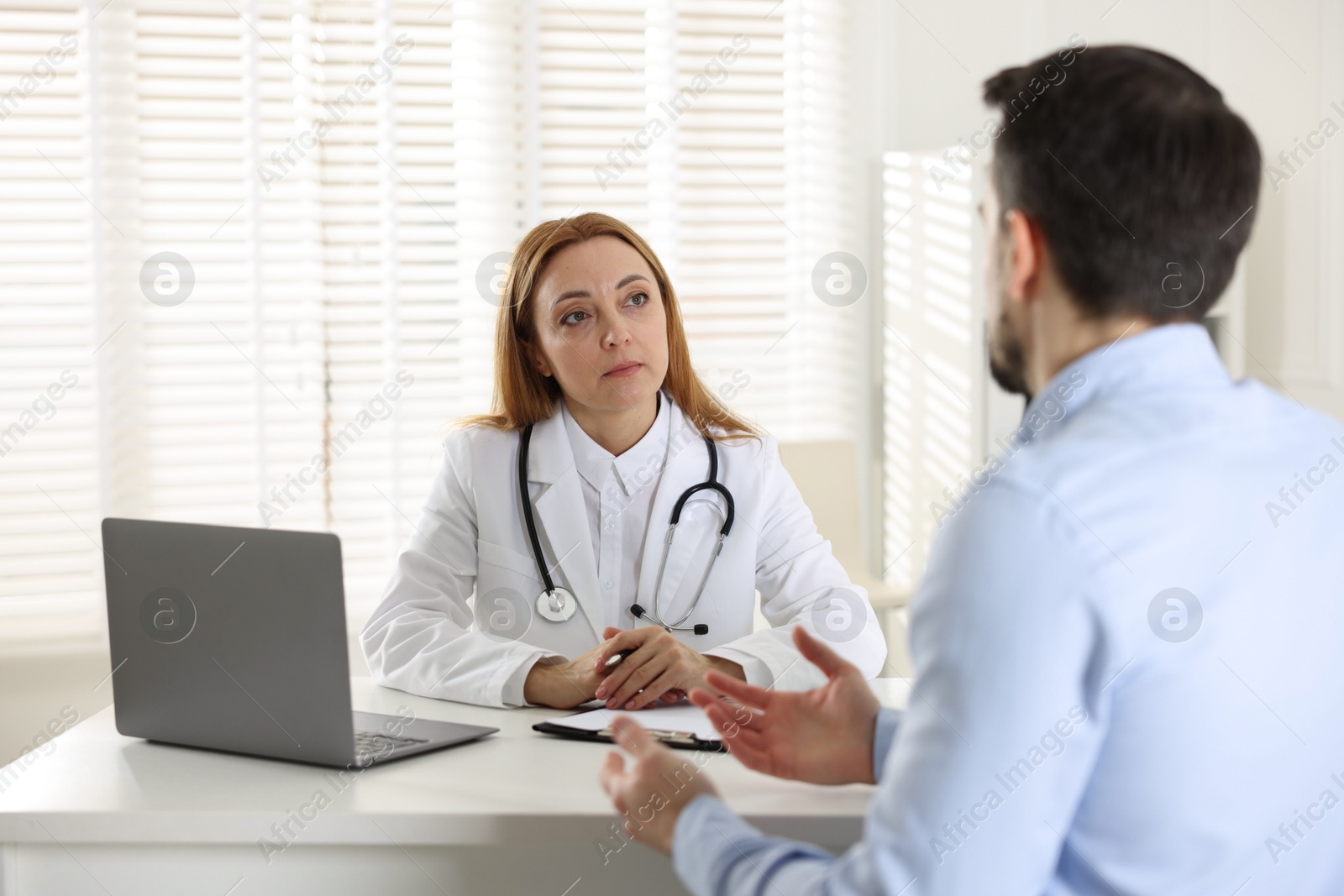 Photo of Man having consultation with cardiologist at desk in clinic