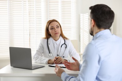 Photo of Man having consultation with cardiologist at desk in clinic