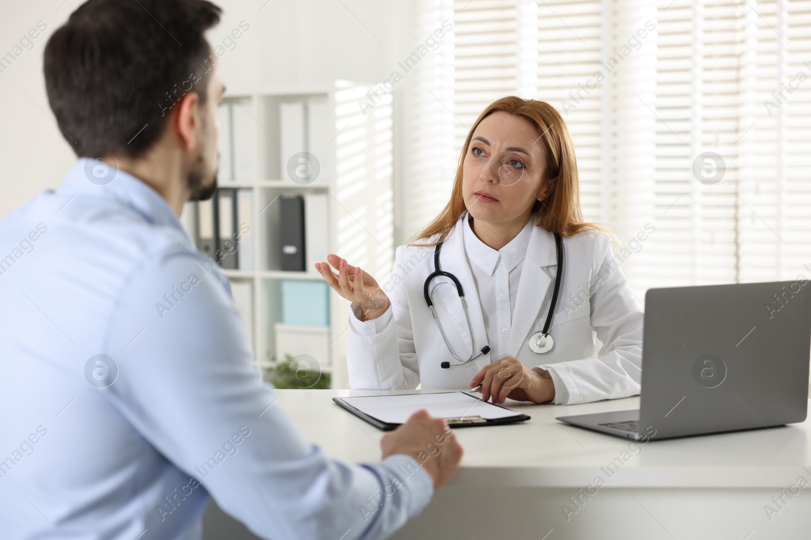 Photo of Man having consultation with cardiologist at desk in clinic