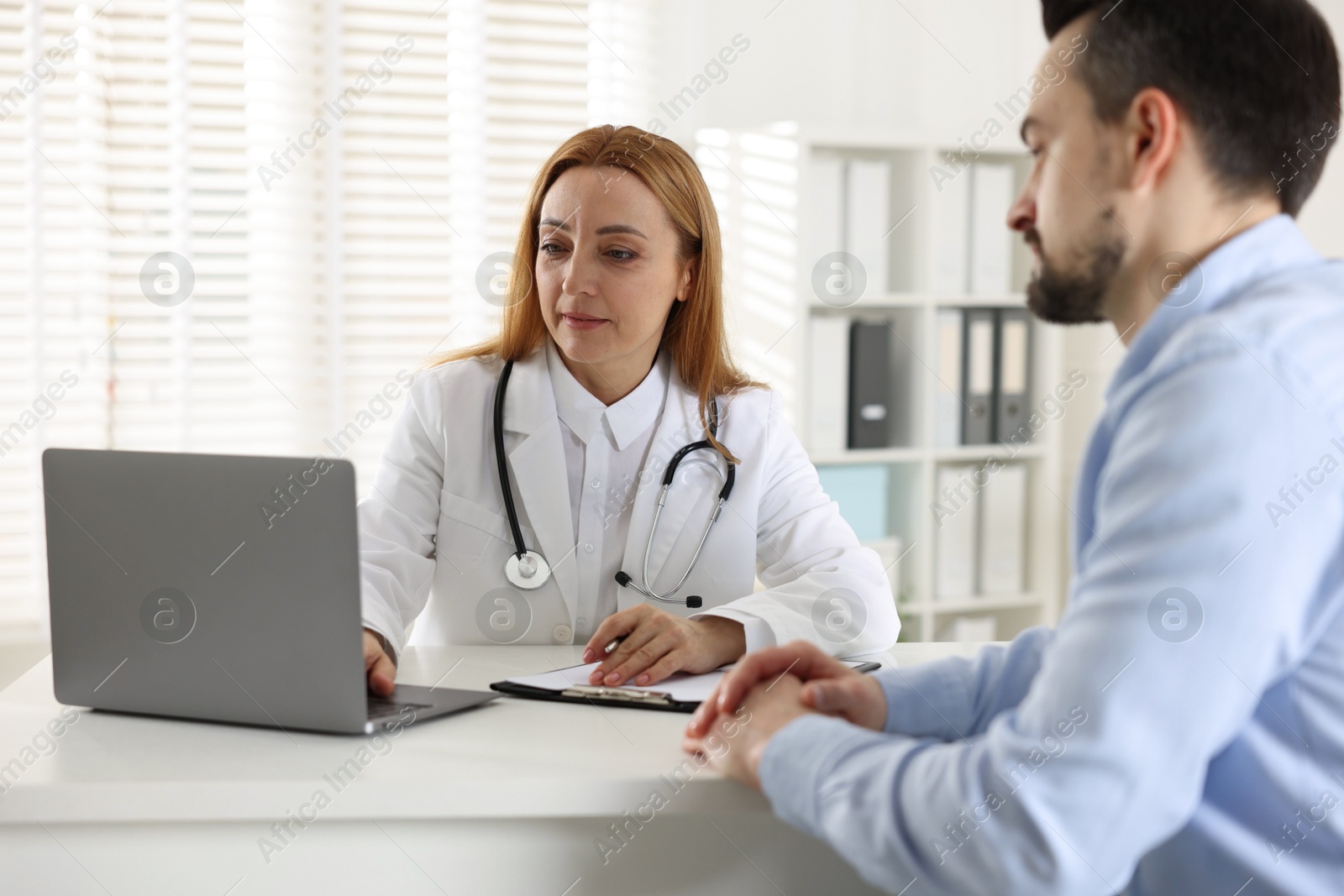 Photo of Man having consultation with cardiologist at desk in clinic