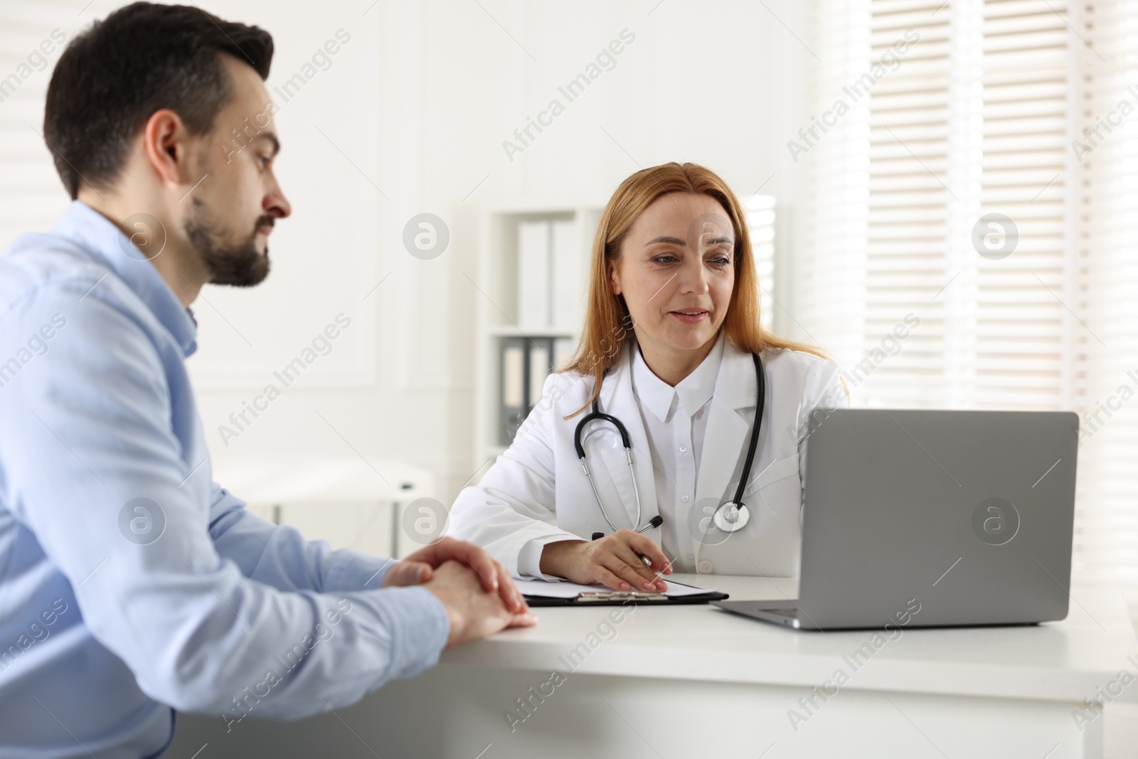 Photo of Man having consultation with cardiologist at desk in clinic