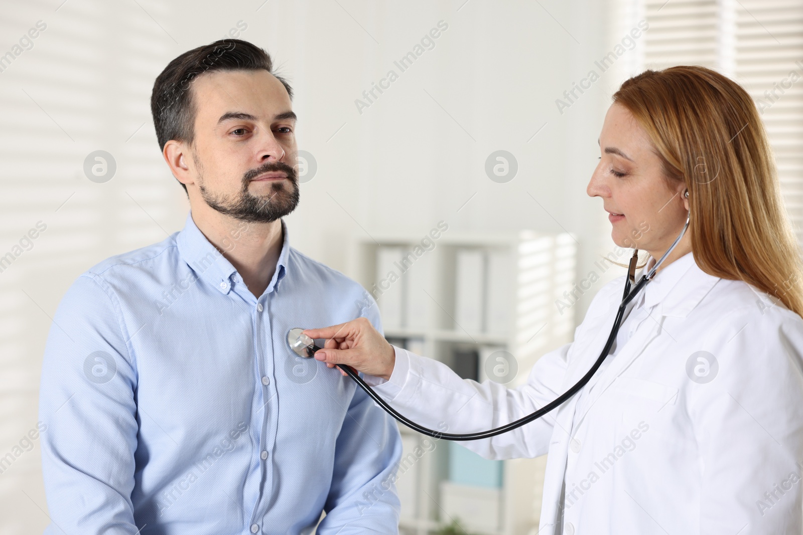 Photo of Cardiologist with stethoscope listening patient's heartbeat in clinic