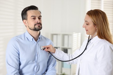 Cardiologist with stethoscope listening patient's heartbeat in clinic