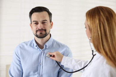 Photo of Cardiologist with stethoscope listening patient's heartbeat in clinic