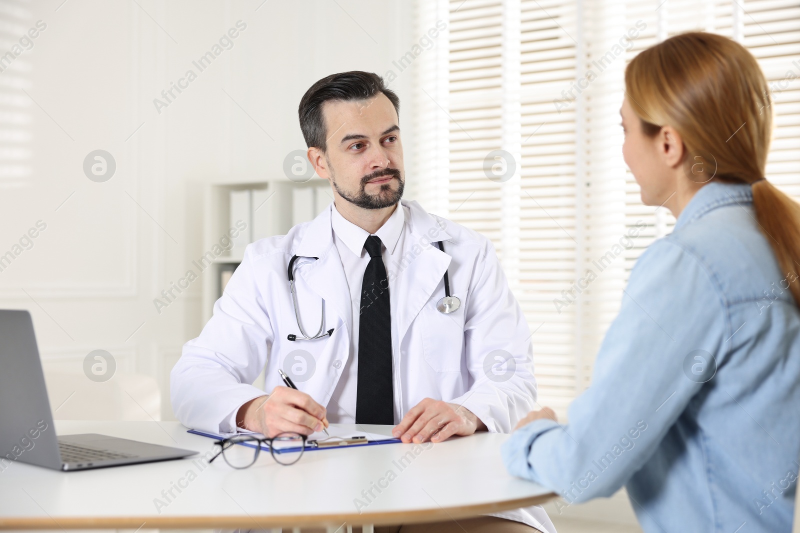 Photo of Cardiologist consulting patient at table in clinic